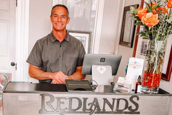 David O'Hara, new resident tour guide and real estate broker and mortgage broker, smiling behind the redlands visitor center front desk