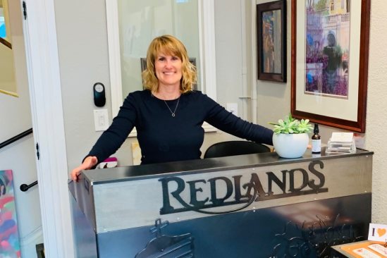 Deborah O'Hara, owner about redlands network and center founder smiling behind the front desk of the redlands visitor center