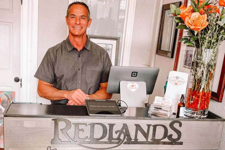 co-founder of the Redlands Visitor Center smiling at front desk