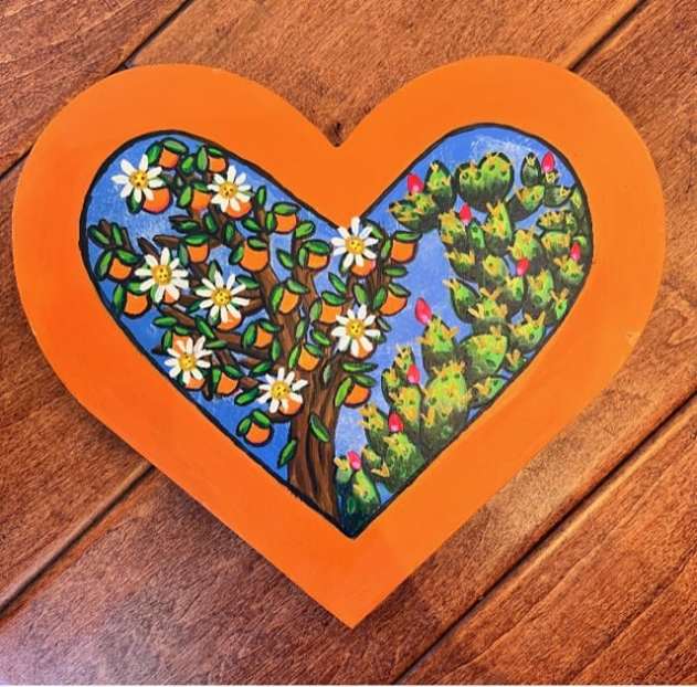 A heart-shaped painting of an orange tree and cactus