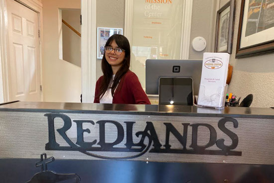 Paula, smiling at the Redlands Visitor Center front desk